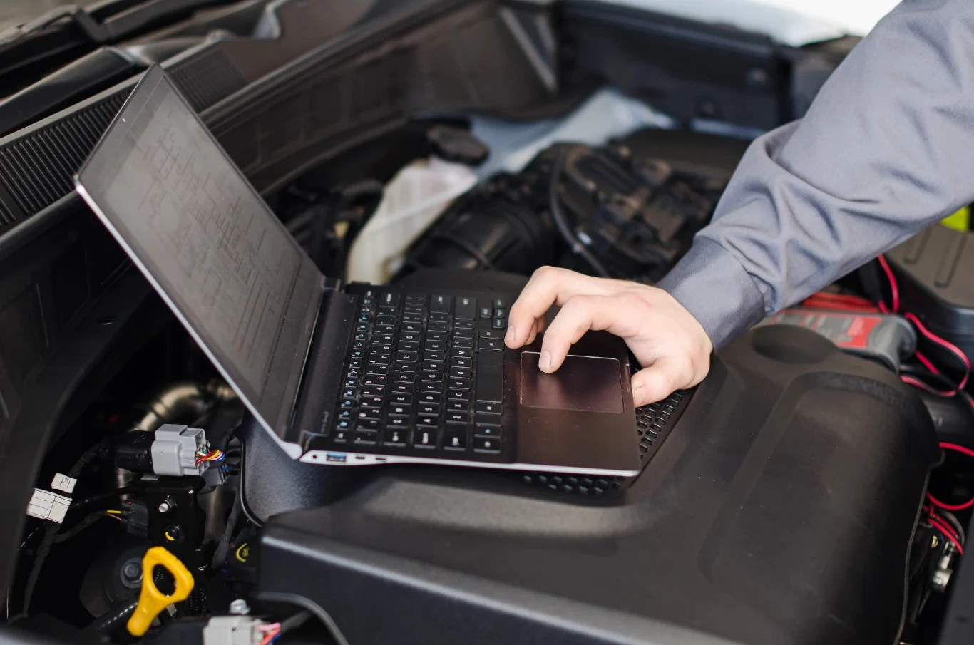Moduły do oszczędzania paliwa - eksperci sprawdzili, czy te gadżety naprawdę działają Mechanik sprawdza silnik samochodu za pomocą laptopa podczas testowania modułu oszczędzania paliwa.