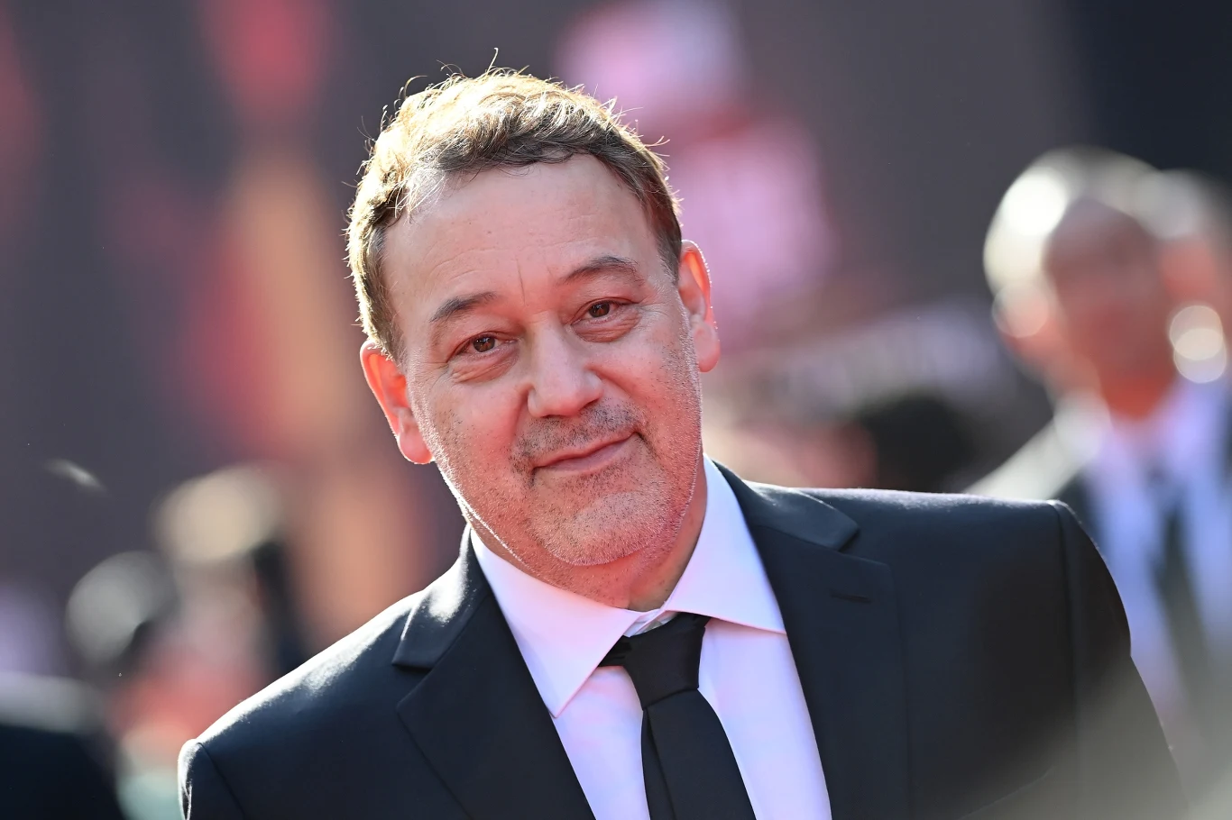 Sam Raimi Sam Raimi w garniturze i krawacie stoi na czerwonym dywanie podczas oficjalnego wydarzenia.