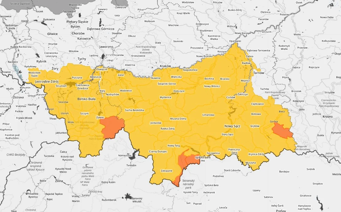 Mapa województwa małopolskiego z zaznaczonymi na żółto obszarami dominującymi oraz wyraźnie wyróżnionymi na pomarańczowo wybranymi powiatami i miastami, na tle sieci granic administracyjnych i nazw miejscowości.
