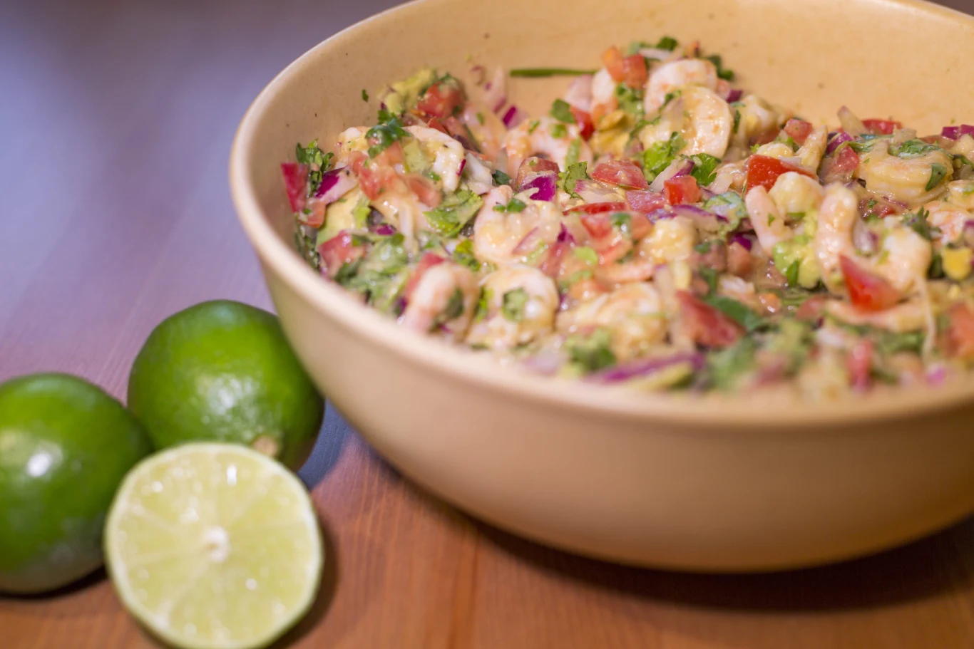 Ceviche z krewetkami to wyjątkowo smaczna i lekka przystawka z Peru Ceviche z krewetkami, czerwoną cebulą, pomidorami, kolendrą i awokado w misce, obok limonki.