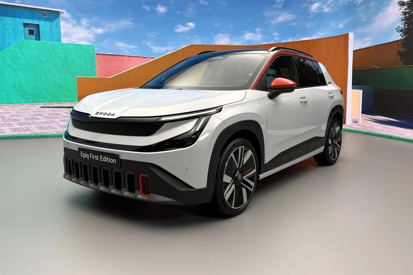 Nowoczesny SUV Skoda o futurystycznym designie, białym lakierze z czarnymi i czerwonymi akcentami, ustawiony na tle kolorowych geometrycznych ścian.