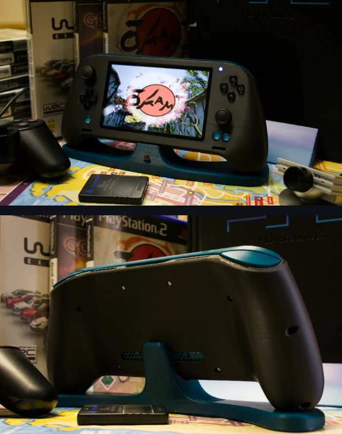 Autorskie PlayStation 2 / źródło: GitHub Przenośna konsola do gier z dużym ekranem w stacji dokującej, otoczona akcesoriami i pudełkami do gier PlayStation na kolorowej powierzchni.