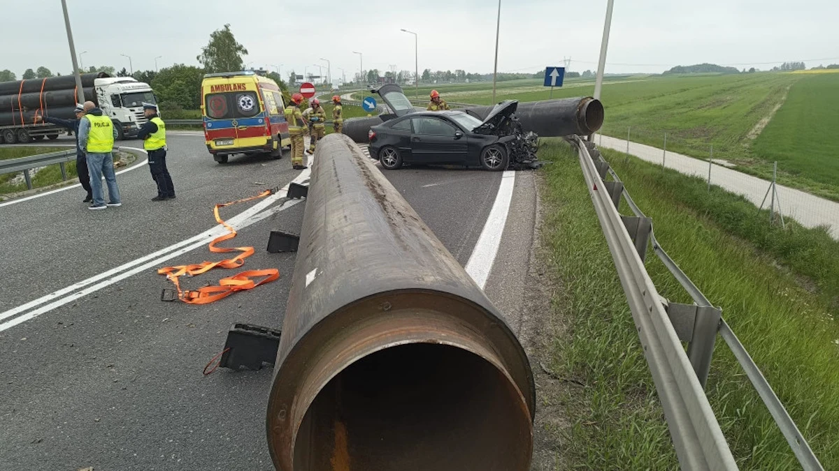 Wypadek wyglądał dramatycznie. Kierująca Mercedesem trafiła do szpitala / Fot: Straż pożarna Czarny Mercedes po zderzeniu ze stalowymi rurami na jezdni, służby ratunkowe i karetka na miejscu wypadku.