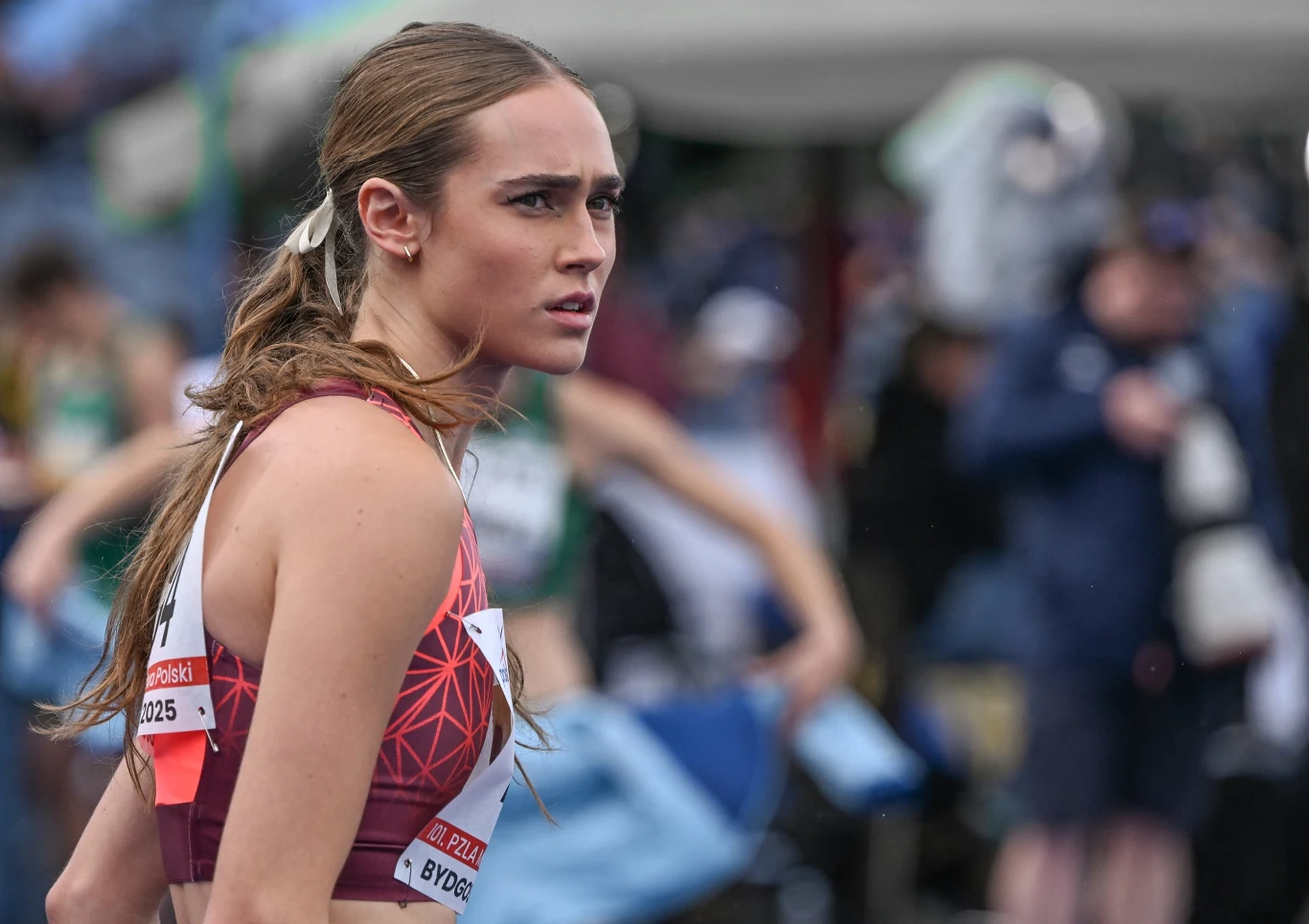 Anastazja Kuś Kobieta w sportowym stroju z numerem startowym, skoncentrowana i skupiona, stoi na bieżni lekkoatletycznej podczas zawodów.