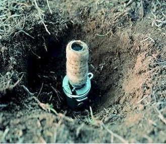 W wykopanej w ziemi jamie znajduje się metalowy cylinder z wystającą, nawiniętą szpulą o jasnej powierzchni.