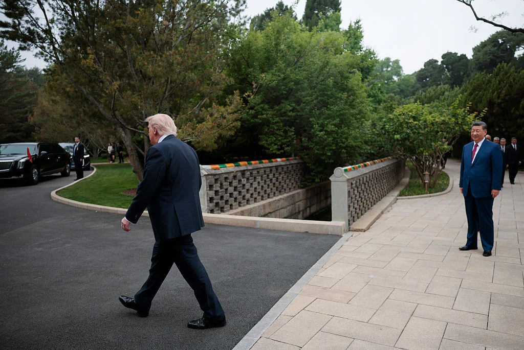 Xi Jinping przygląda się, jak amerykańskie imperium oddala się w niebyt? Donald Trump i Xi Jinping w garniturach, Trump wychodzi, Jinping przygląda mu się na ścieżce, zieleń i limuzyny w tle.