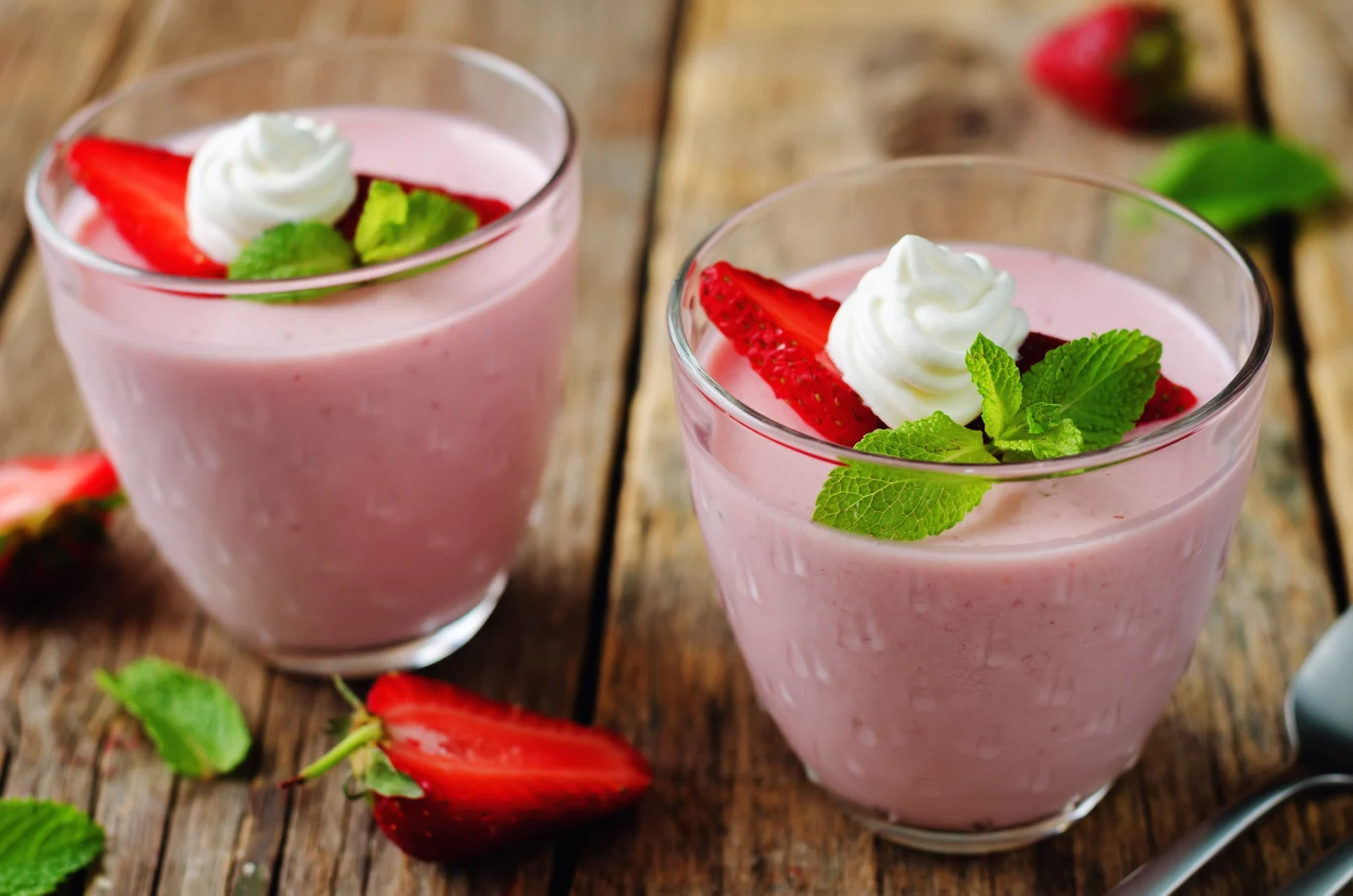 Truskawkowa panna cotta to hit wakacyjnych deserów Dwie truskawkowe panny cotty w szklankach.