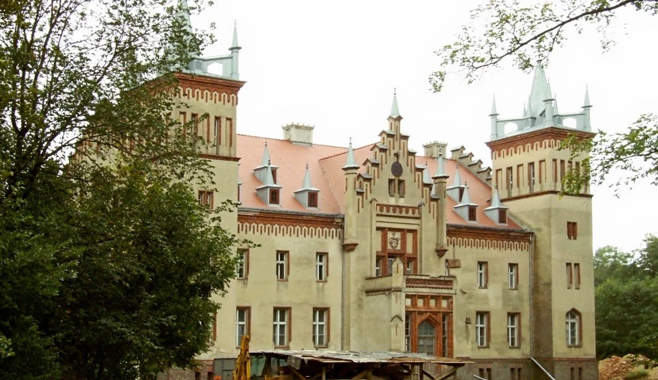 Pałac przez lata należał do Jana A.P. Kaczmarka Okazały pałac w stylu neogotyckim z czterema wysokimi wieżami, czerwonym dachem i ozdobnymi szczytami, otoczony drzewami.