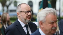 Dwóch mężczyzn w garniturach w trakcie oficjalnego wydarzenia na świeżym powietrzu.