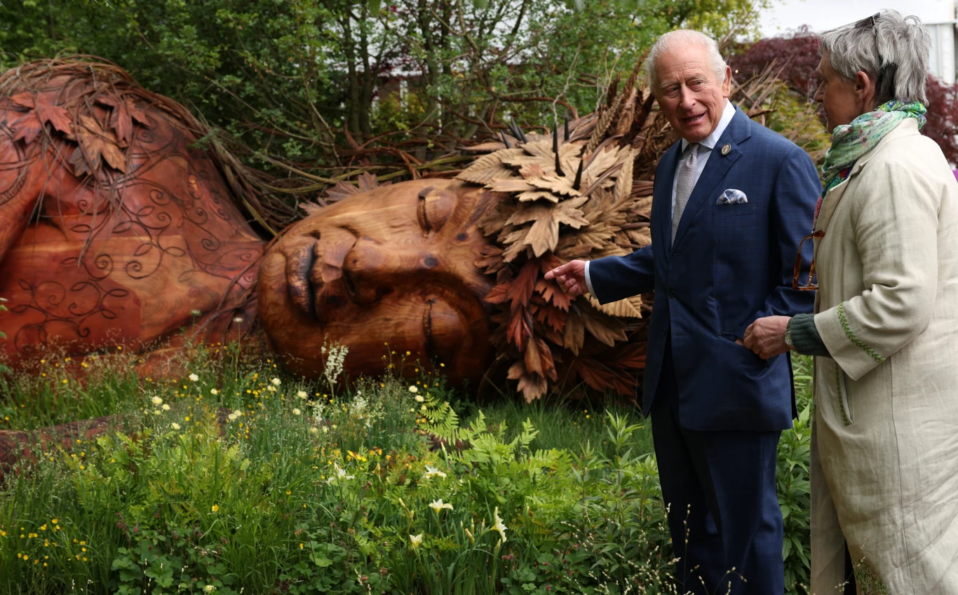Król Karol III odwiedził ogrody na Chelsea Flower Show 2026 już w poniedziałek Para stojąca przed dużą rzeźbą przedstawiającą śpiącą kobietę z zamkniętymi oczami, ozdobioną liśćmi, w otoczeniu zieleni i kwiatów.