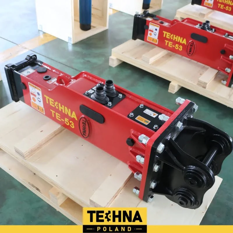 Hydrauliczny młot wyburzeniowy TEHNA TE-53 w czerwonym kolorze, umieszczony na drewnianej palecie na hali produkcyjnej, z wyraźnym oznaczeniem producenta i modelu.