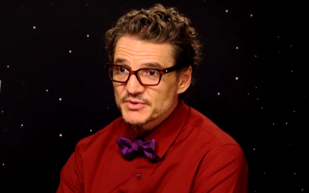 Pedro Pascal w wywiadzie Maksa Behra Mężczyzna w bordowej koszuli i fioletowej muszce, w okularach, na tle czarnego nieba z gwiazdami.
