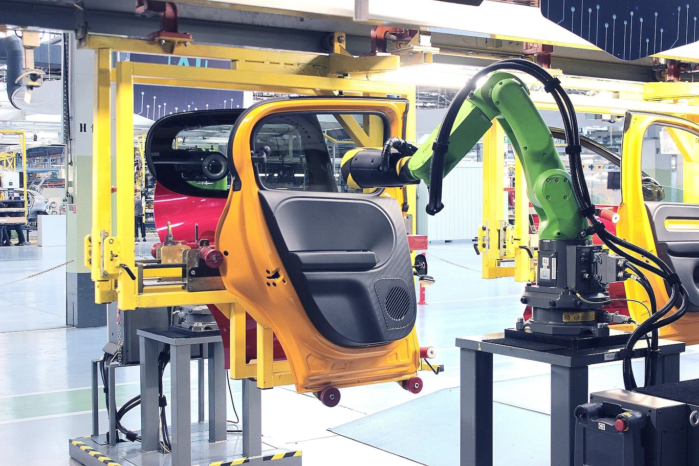 Ramię robota montuje drzwi samochodowe na linii produkcyjnej w nowoczesnej fabryce motoryzacyjnej.