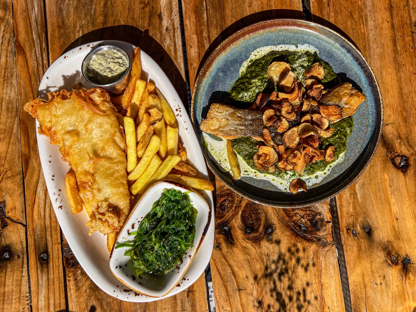 Wycieczki z lokalnymi przewodnikami obfitują w wiele wrażeń, także kulinarnych Porcja panierowanej ryby z frytkami i zieloną sałatką, obok talerz z grillowaną rybą na sosie szpinakowym, udekorowaną plasterkami smażonego czosnku.