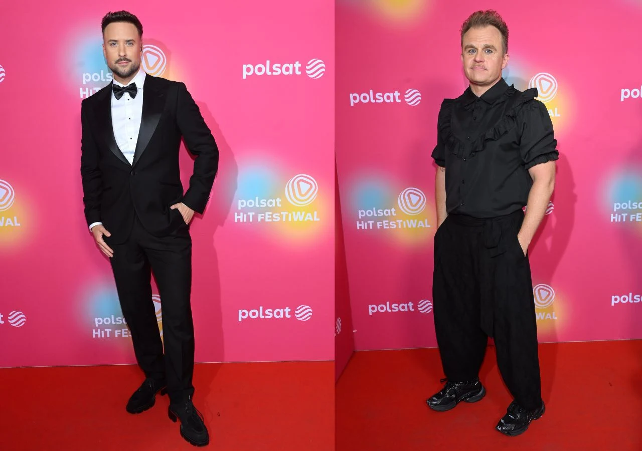 Polsat Hit Festiwal 2026 - dzień drugi. Aleksander Sikora i Piotr Rogucki Dwóch mężczyzn pozujących na czerwonym dywanie przed ścianką z logo Polsat Hit Festival; jeden ubrany w elegancki smoking z muchą, drugi w luźny, czarny strój z falbanami na koszuli.