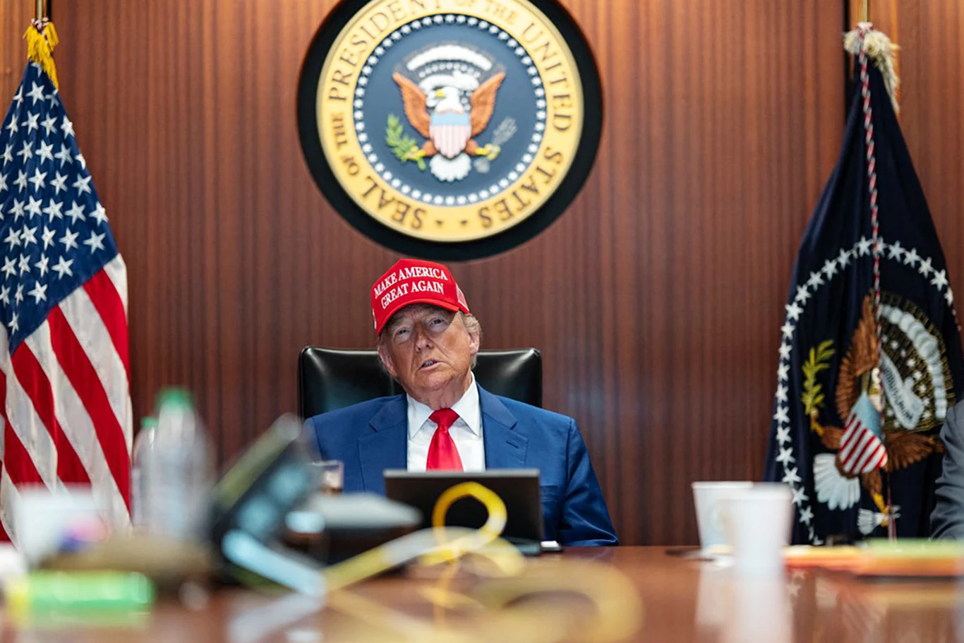 Prezydent Donald Trump w Situation Room w 2025 roku w czasie pierwszego ataku na Iran Donald Trump w czerwonej czapce MAGA siedzi przy stole w Situation Room, otoczony flagami USA i prezydenckim godłem.