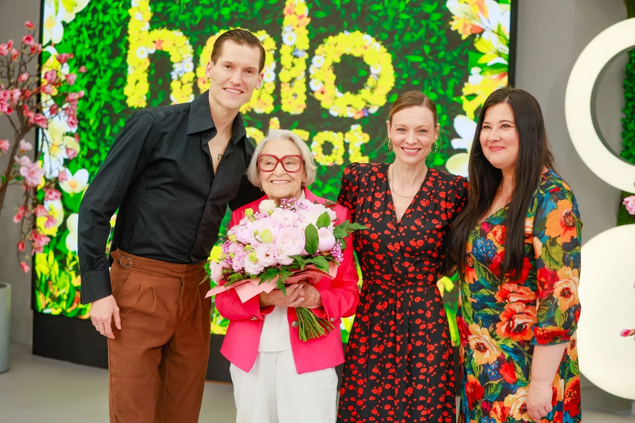 Jacek Jeschke, Teresa Godlewska, Magdalena Boczarska, Gabriela Gardaś Cztery uśmiechnięte osoby pozują razem na tle kolorowej, kwiatowej dekoracji, kobieta pośrodku trzyma bukiet kwiatów.