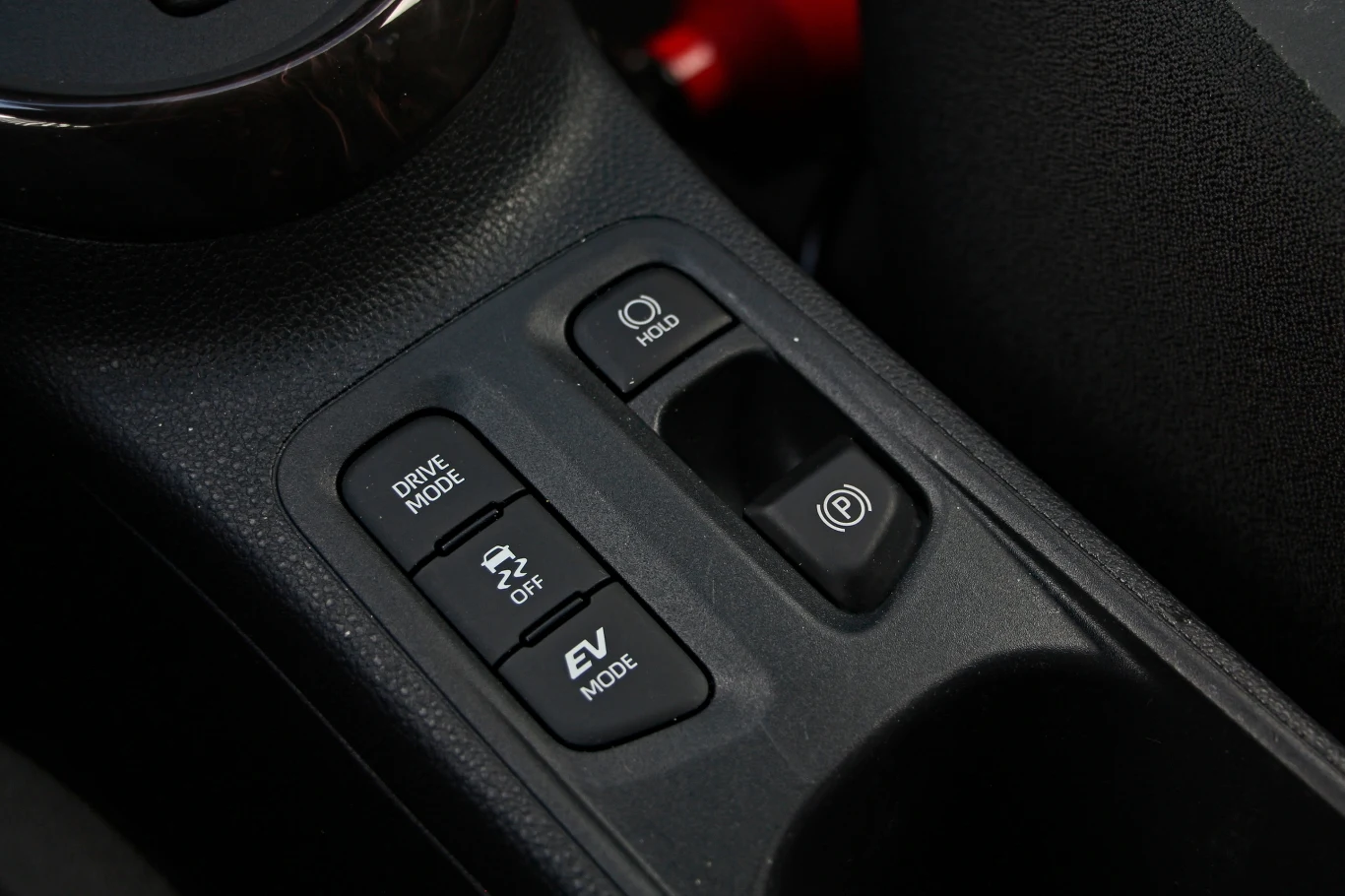 Aygo X Hybrid otrzymało także elektryczny hamulec ręczny z auto holdem oraz przełącznik trybów jazdy Panel sterowania w samochodzie z przyciskami do wyboru trybu jazdy, ustawienia trakcji, trybu elektrycznego oraz elektronicznym hamulcem postojowym i funkcją auto hold.