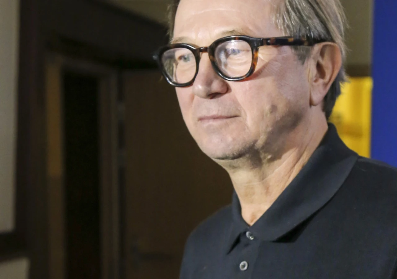 Piotr Cyrwus Aktor Piotr Cyrwus ubrany w czarną koszulkę polo oraz okulary.