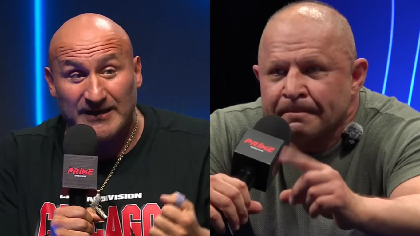 Dwóch łysych mężczyzn rozmawiających do mikrofonów podczas debaty, z poważnymi wyrazami twarzy i skupieniem na rozmowie.