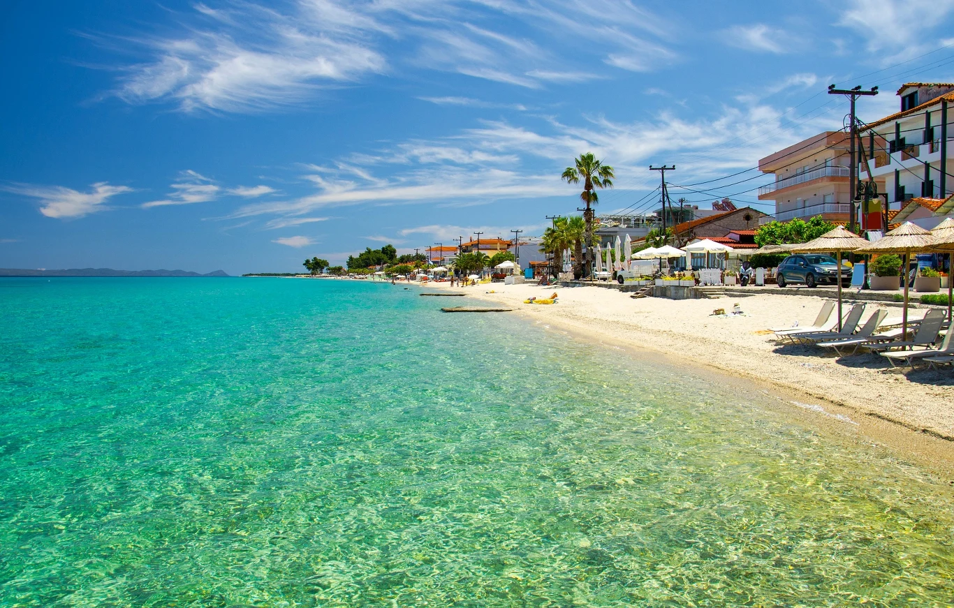 Plaże w okolicy Possidi oferuję niezwykle czyste morze Turkusowa, przejrzysta woda morza, jasna, piaszczysta plaża z leżakami i parasolami oraz budynki i restauracje usytuowane wzdłuż wybrzeża pod jasnym, słonecznym niebem.