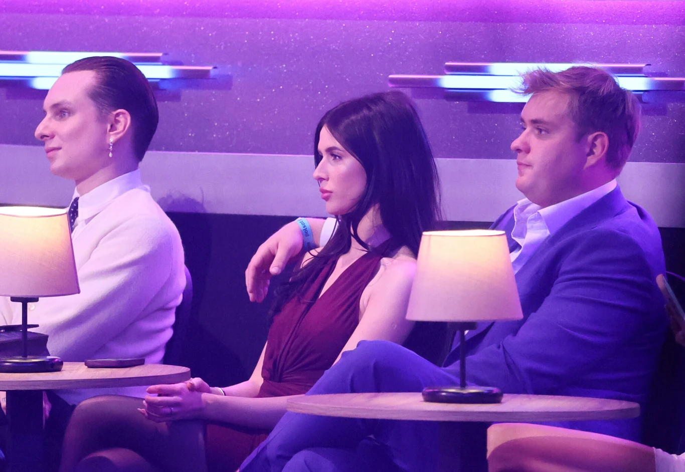 Ralph Kaminski, Roxie Węgiel, Kevin Mglej Ralph Kaminski, Roxie Węgiel oraz Kevin Mglej siedzący przy stoliku w różowo-fioletowym oświetleniu.