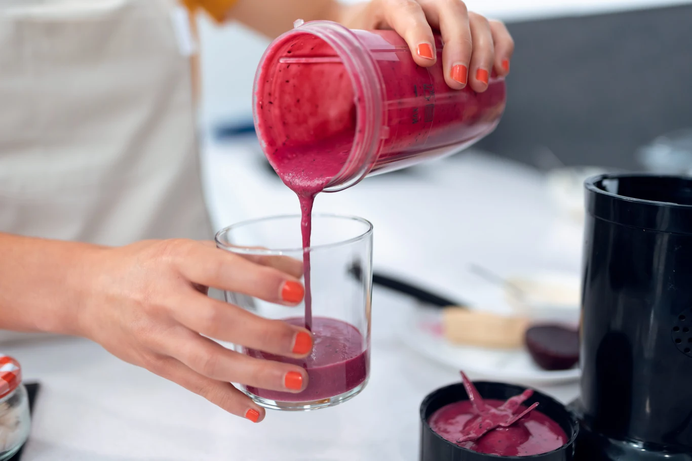 Już 200 ml tego soku, wypitego na czczo, oczyści jelita ze złogów i podkręci metabolizm. Kobieta przelewa gęsty, fioletowy sok z buraka z blendera do szklanki na jasnej kuchennej powierzchni.