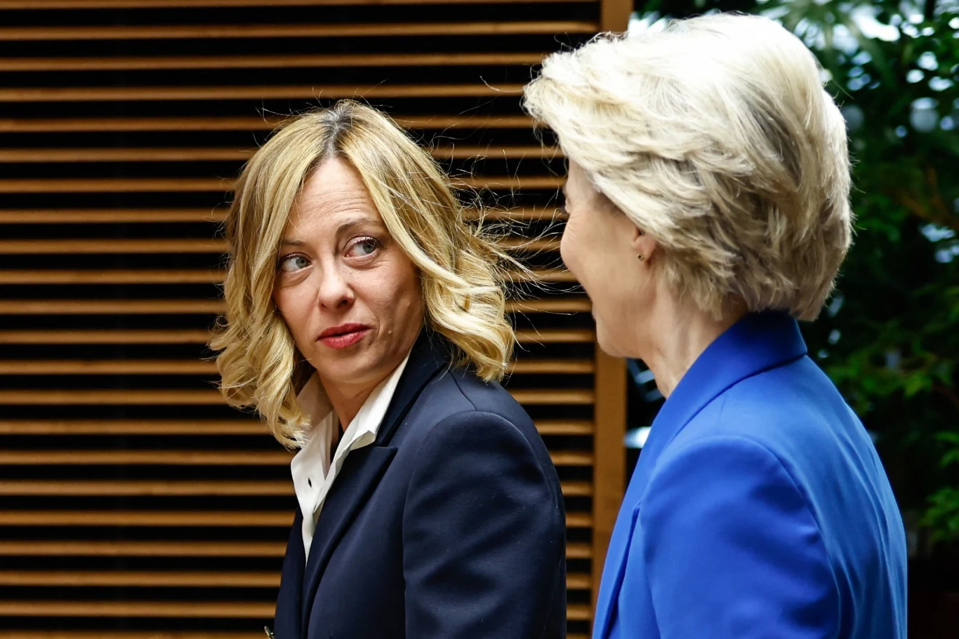 Premier Włoch Giorgia Meloni i przewodnicząca Komisji Europejskiej Ursula von der Leyen, 20 grudnia 2024 r. Dwie kobiety w eleganckich marynarkach stoją obok siebie, prowadząc rozmowę w formalnej, biurowej przestrzeni.