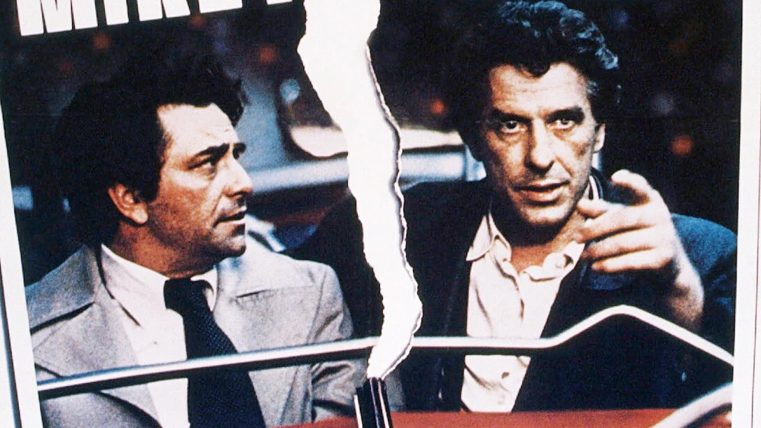 Peter Falk i John Cassavetes na grafice promującej film "Mikey i Nicky" Dwaj mężczyźni w garniturach siedzą obok siebie, oddzieleni rozdarciem przebiegającym przez środek obrazu; jeden z nich spogląda na rozmówcę, drugi wskazuje ręką na coś przed sobą.