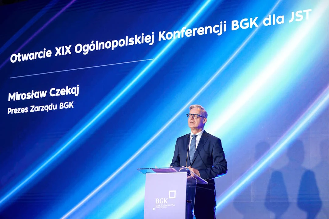 Specjalny fundusz BGK pomaga samorządom Mężczyzna w garniturze przemawia na tle ekranu z informacją o XIX Konferencji BGK dla JST i nazwiskiem Mirosław Czekaj.