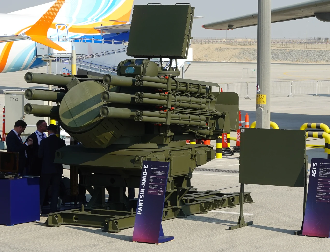 Pancyr-SMD w wersji eksportowej Wielolufowy system rakietowy Pantsir-SM-E w barwie oliwkowej, wyposażony w radar oraz liczne wyrzutnie pocisków, ustawiony na platformie demonstracyjnej podczas pokazu na wolnym powietrzu.