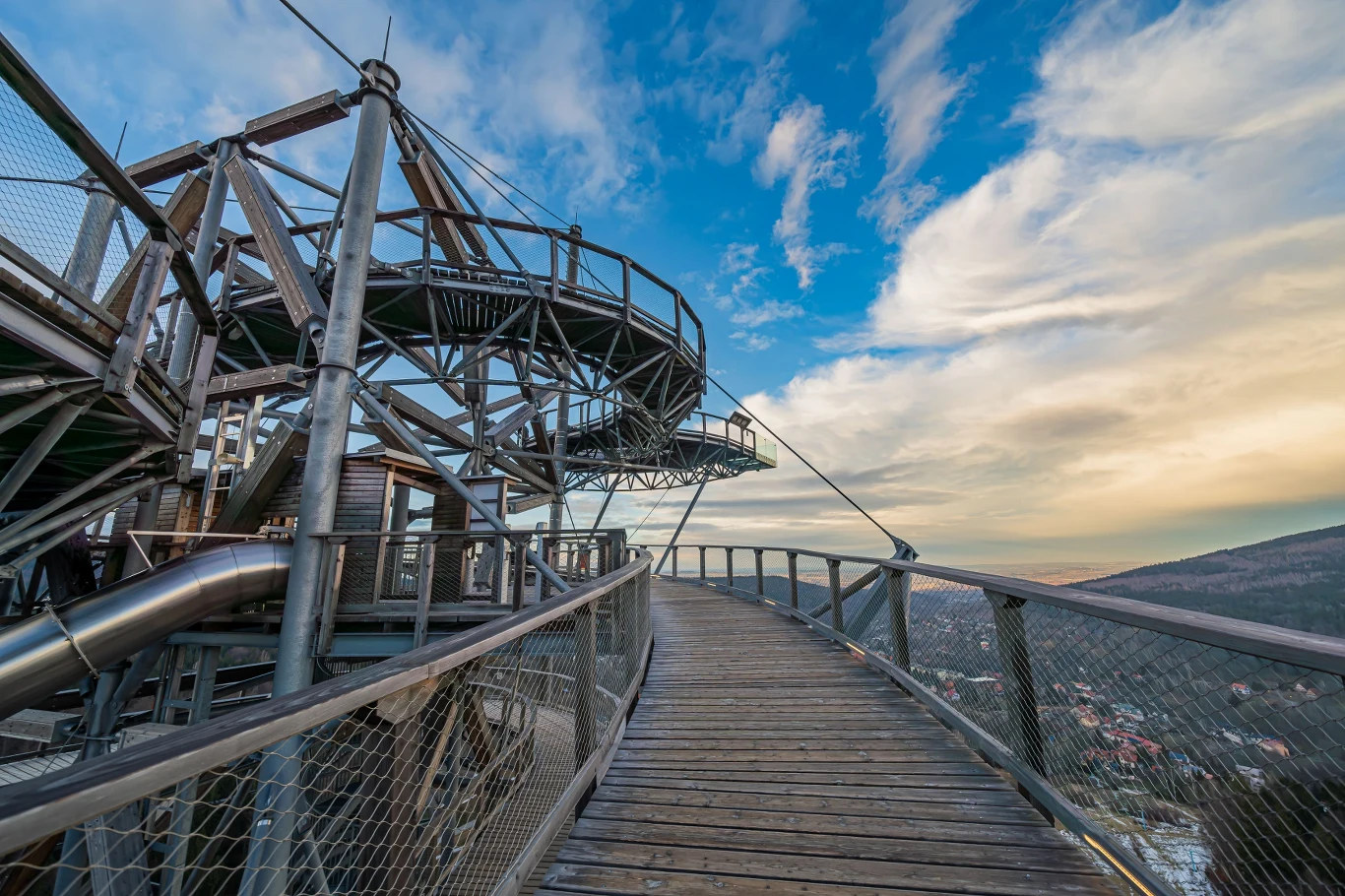 Wieża widokowa w Świeradowie-Zdroju robi wrażenie na turystach Wieża widokowa Sky Walk w Świeradowie-Zdroju z drewnianą ścieżką, platformą i metalową zjeżdżalnią na tle gór