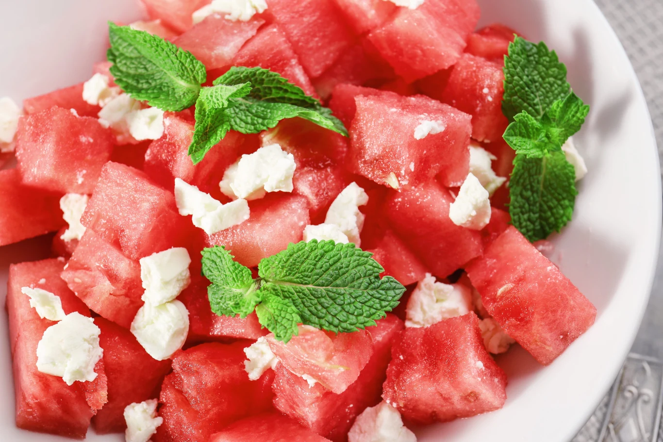Fresh salad with watermelon, close up Sałatka z kawałków arbuza i białej fety, udekorowana świeżymi liśćmi mięty, widok z bliska