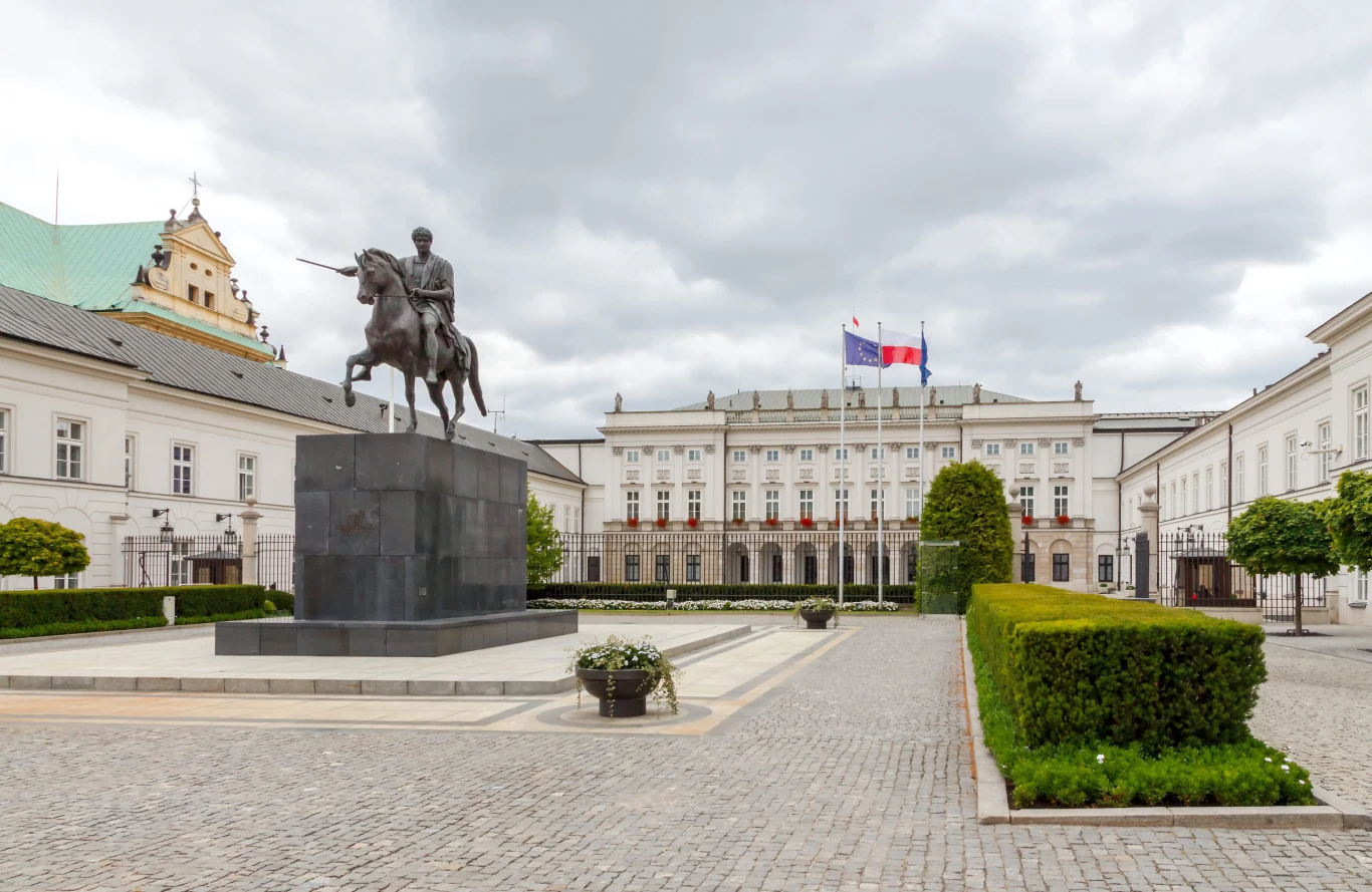 Tyle mogą kosztować konie prezydenta. Leśkiewicz mówi o "propagandowej akcji" Pomnik konny na placu przed pałacem, w tle powiewające flagi i alejki z dekoracyjną zielenią.