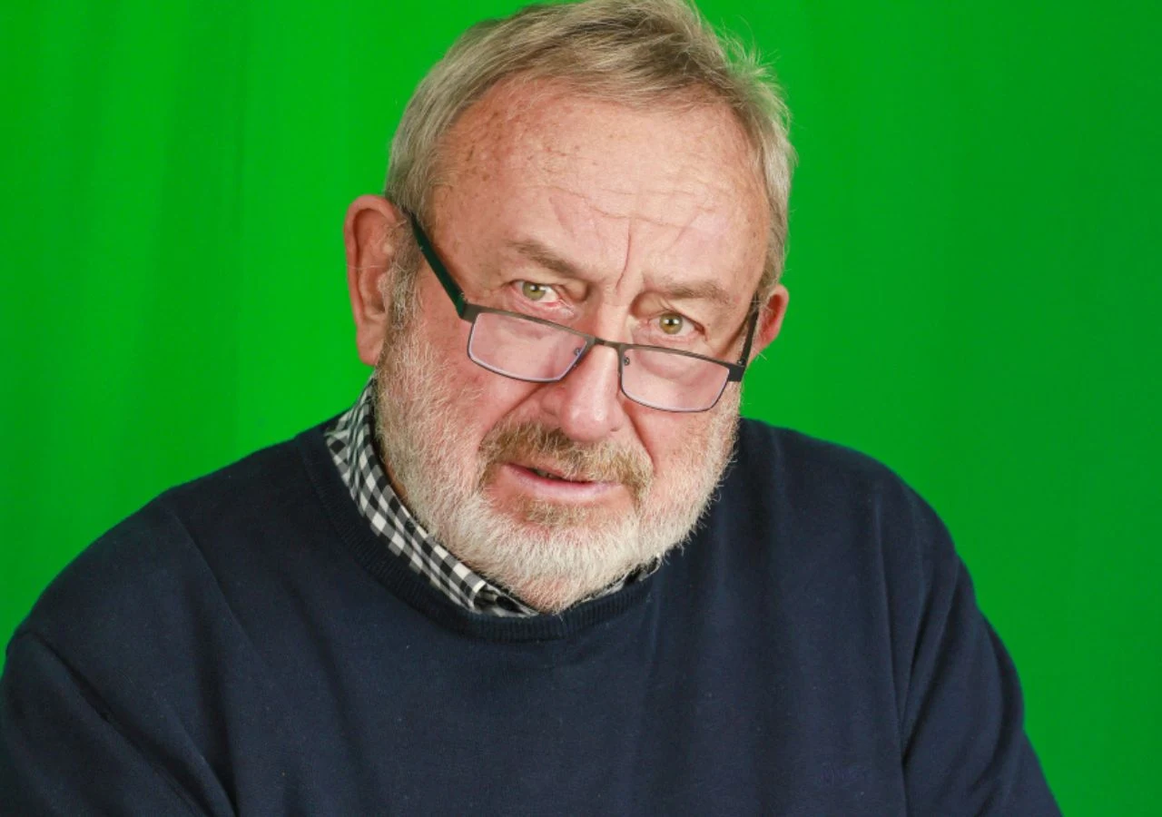 Tadeusz Drozda Tadeusz Drozda, satyryk i artysta kabaretowy, na zielonym tle. Siedzi ze zmartwionym wyrazem twarzy.