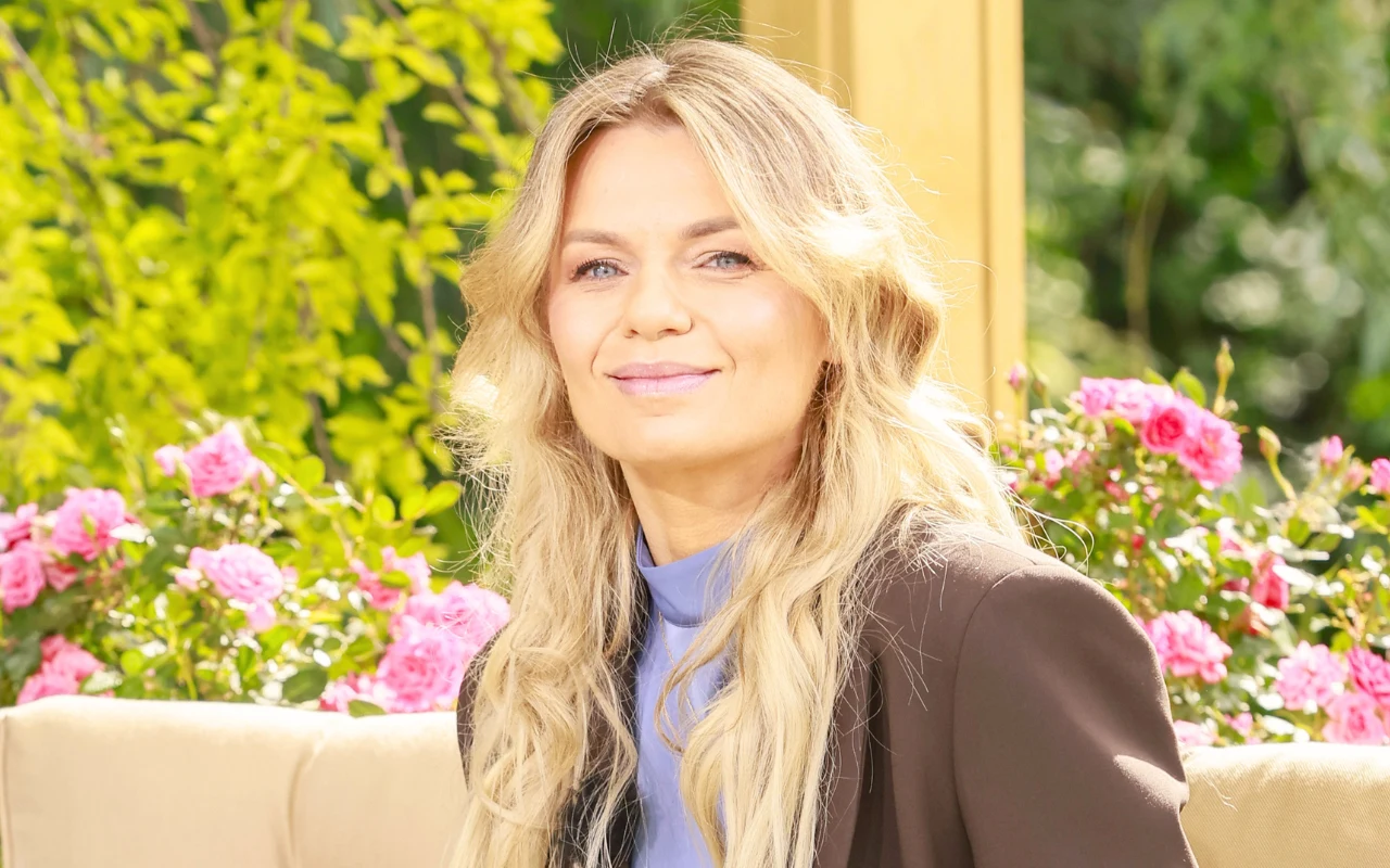 Emilia Komarnicka w "halo tu polsat" Uśmiechnięta Emilia Komarnicka w słonecznej altanie, na jasnej kanapie, w tle kwiaty i drzewa