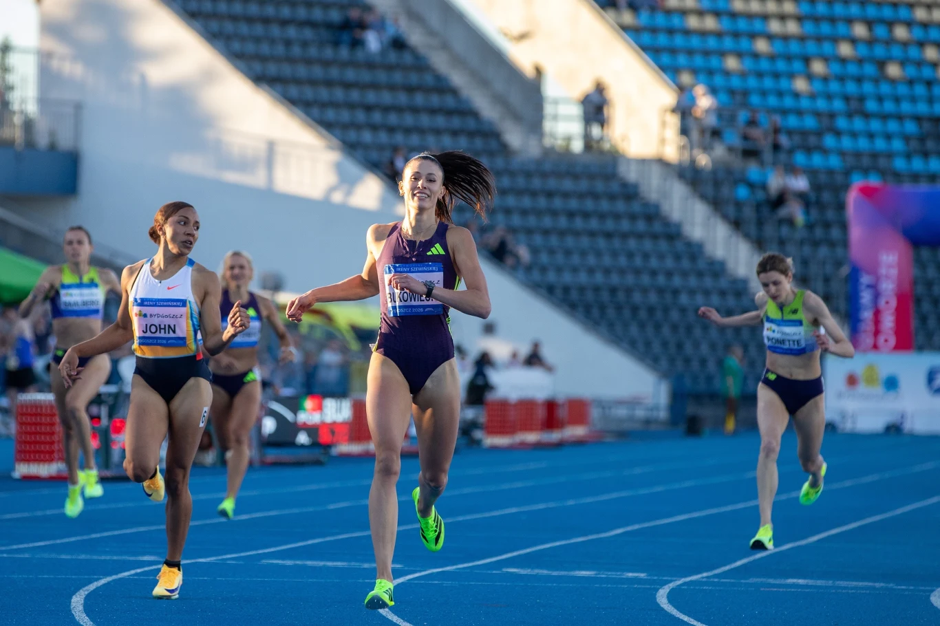 Natalia Bukowiecka w Bydgoszczy Zawodniczki biegnące na niebieskiej bieżni stadionu lekkoatletycznego, jedna z nich wysuwa się zdecydowanie na prowadzenie tuż przed linią mety, pozostałe próbują ją dogonić.