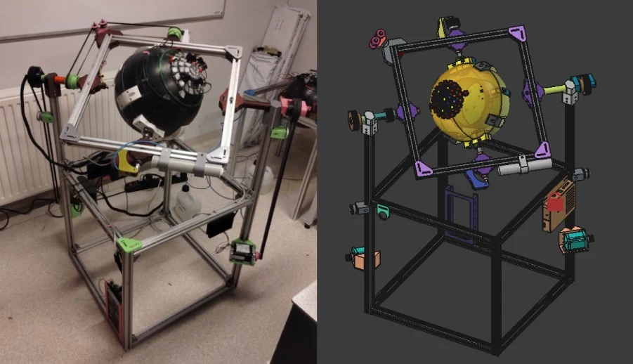 Metalowa rama w kształcie sześcianu z zamocowaną na środku kulistą konstrukcją techniczną i szeregiem kolorowych, narożnych uchwytów, obok widoczny model 3D tego samego urządzenia.