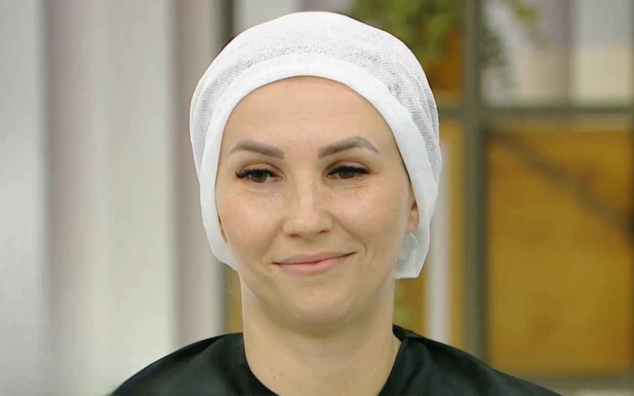 Kobieta z delikatnym makijażem, uśmiechnięta, w białym czepku ochronnym na głowie.
