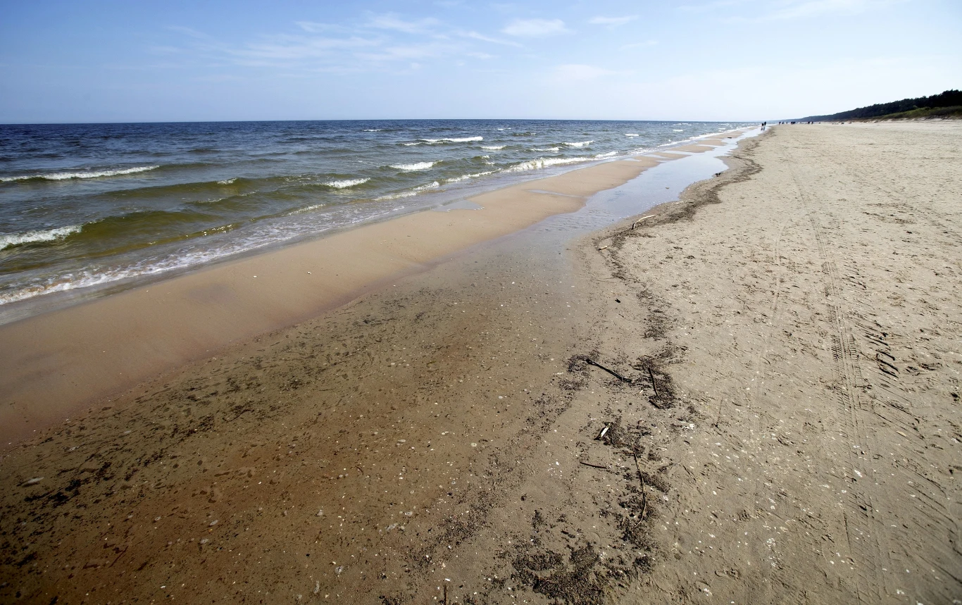 Na plaży w Jantarze jest duża szansa na znalezienie bursztynu. Szeroka, piaszczysta plaża nad morzem z łagodnie rozbijającymi się falami i pustą linią brzegową ciągnącą się wzdłuż horyzontu.