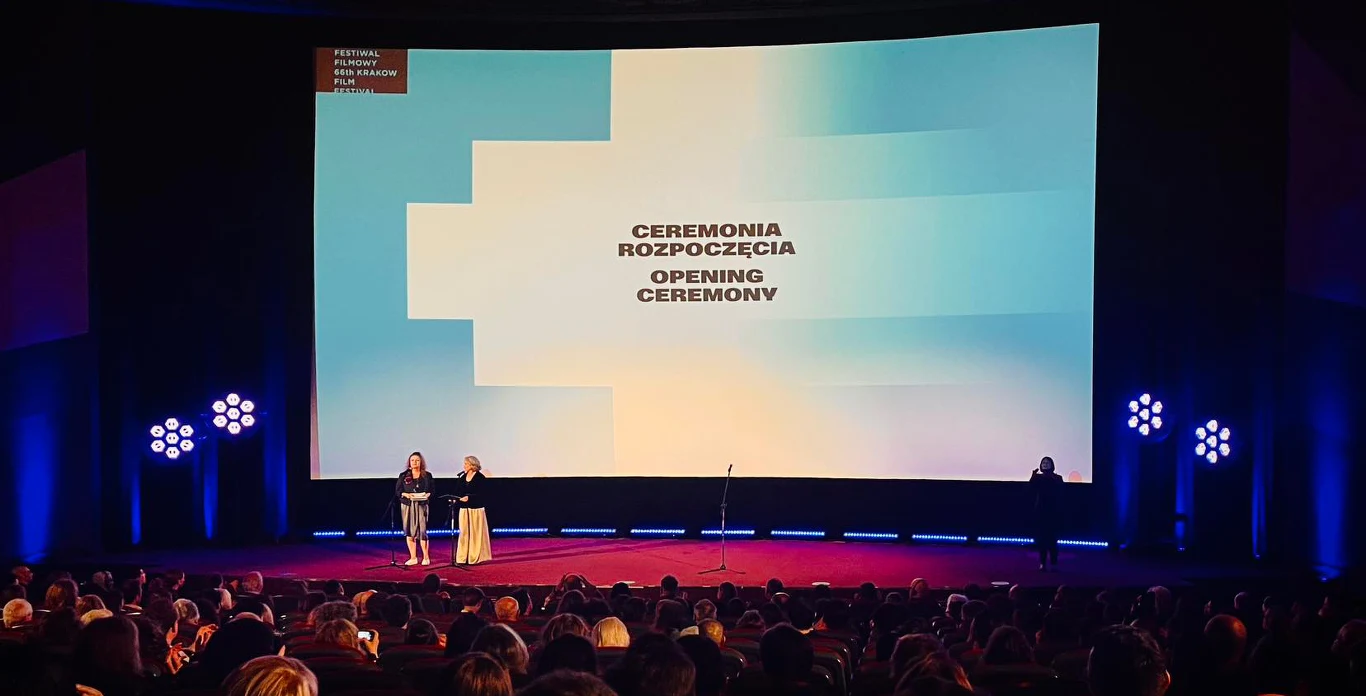 Ceremonia otwarcia 66. Krakowskiego Festiwalu Filmowego Dwie osoby na scenie podczas otwarcia 66. Krakowskiego Festiwalu Filmowego, tłum widzów, napis "Ceremonia rozpoczęcia"
