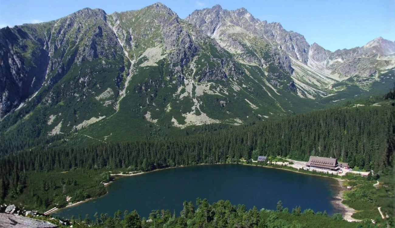 Popradzki Staw w Dolinie Mięguszowieckiej na Słowacji Popradzki Staw w Dolinie Mięguszowieckiej, otoczony świerkowym lasem i szczytami, schronisko przy brzegu.