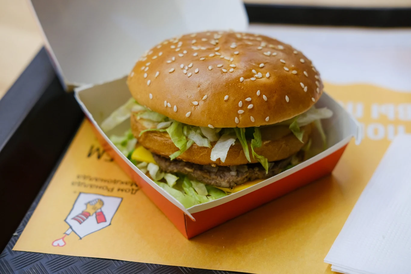 Ile kosztuje jedzenie w fast foodzie w Norwegii? Polak pokazał ceny. Burger z dwoma warstwami wołowiny, sałatą i serem w sezamowej bułce, w kartonowym opakowaniu na tacki.