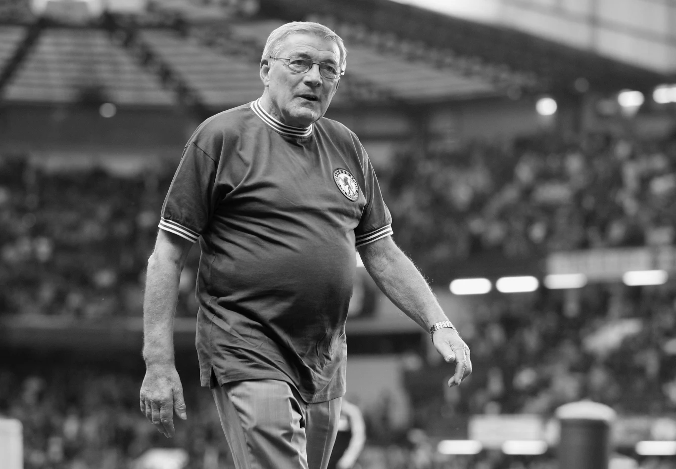 Bobby Tambling, zdjęcie z roku 2013 Bobby Tambling w 2013 roku na stadionie, w okularach i sportowej koszulce z herbem klubu, podczas meczu.