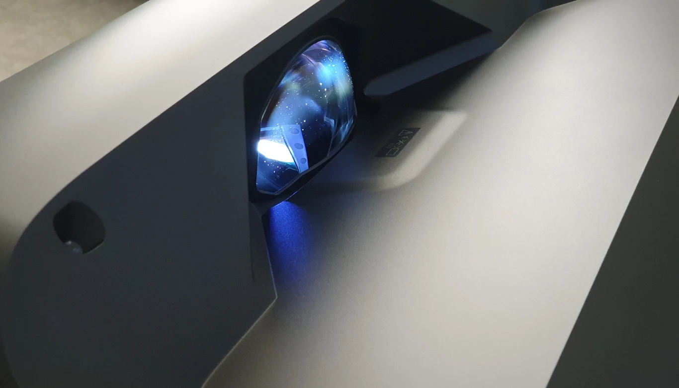 Lifestudio Grand EH-LS670 Projektor Epson Lifestudio Grand EH-LS670 zbliżenie na obiektyw emitujący niebieskie światło, nowoczesna obudowa.