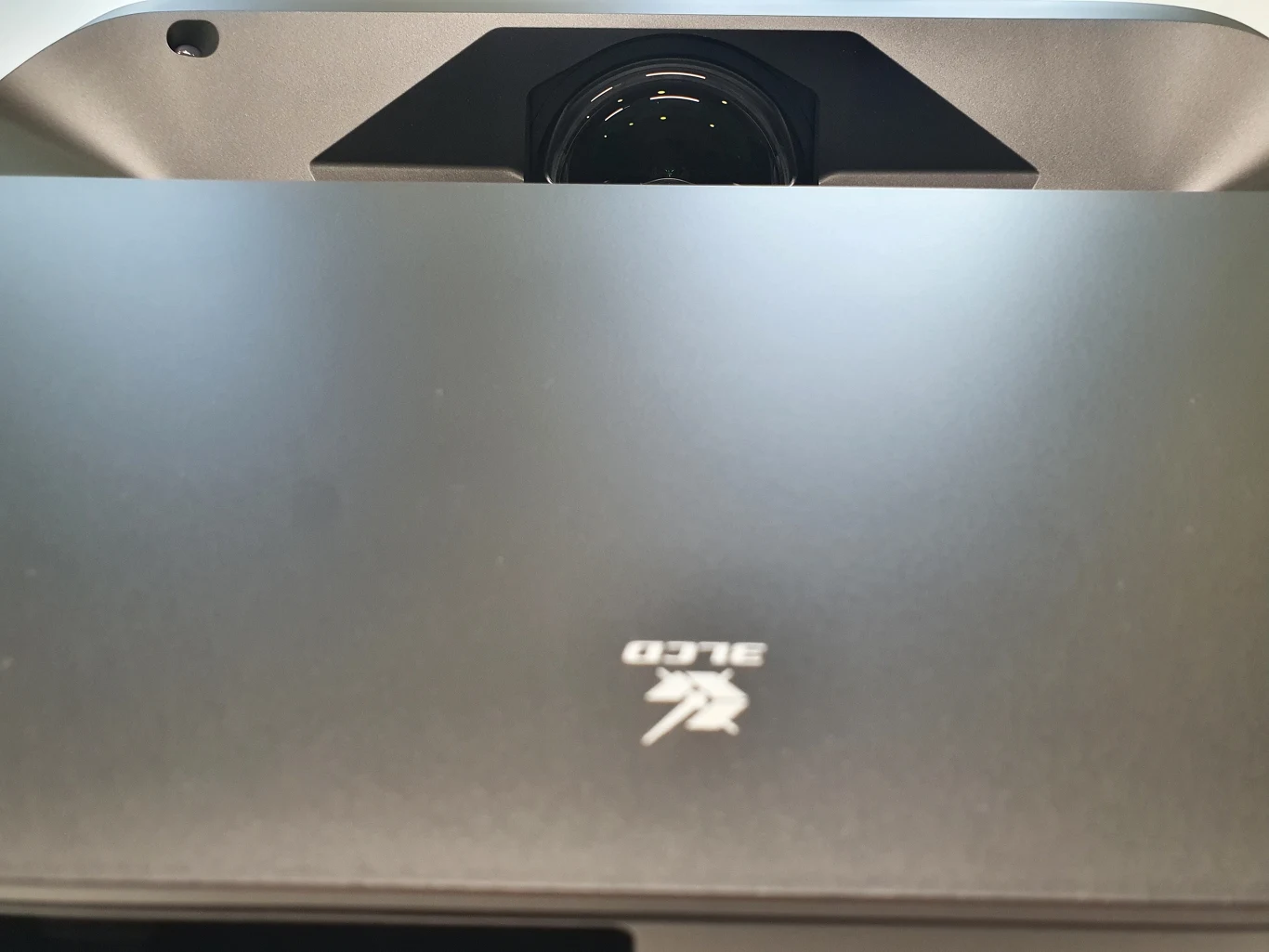 Lifestudio Grand EH-LS670 Obiektyw projektora laserowego z logo ALPD na obudowie, ustawionego na krótkim dystansie do powierzchni projekcyjnej.