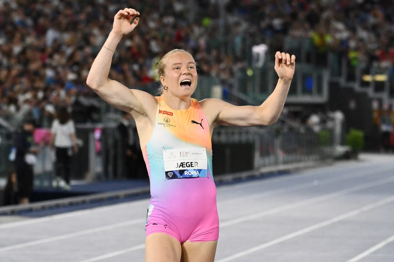 Henriette Jaeger, Rzym 2026 Zawodniczka w kolorowym stroju lekkoatletycznym z wyciągniętymi w górę ramionami wyraża radość na bieżni stadionu, wokół gęsta publiczność na trybunach.