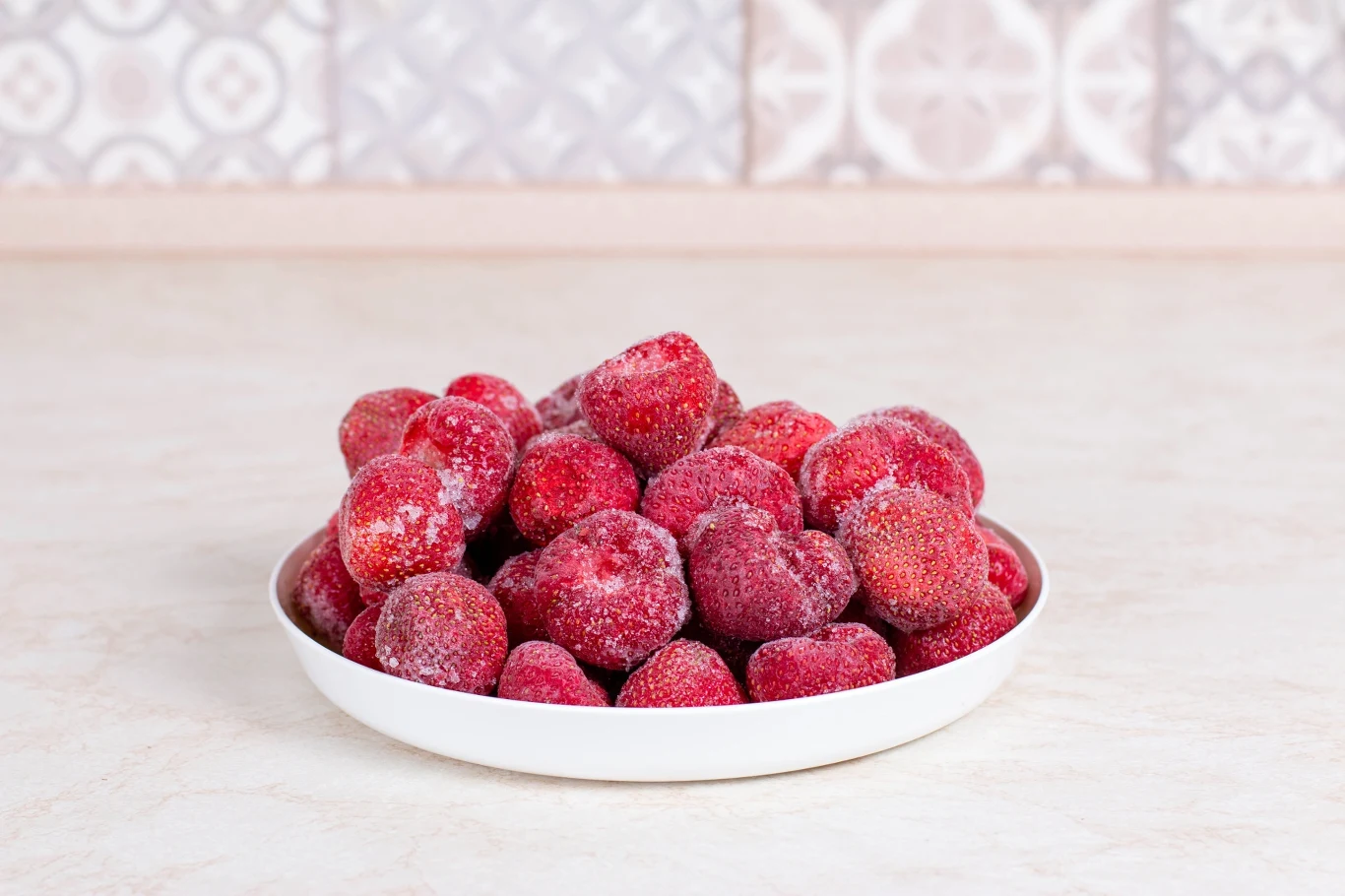 Sorbet truskawkowy najszybciej zrobisz z mrożonych owoców Miska wypełniona mrożonymi truskawkami, których powierzchnia pokryta jest cienką warstwą szronu.