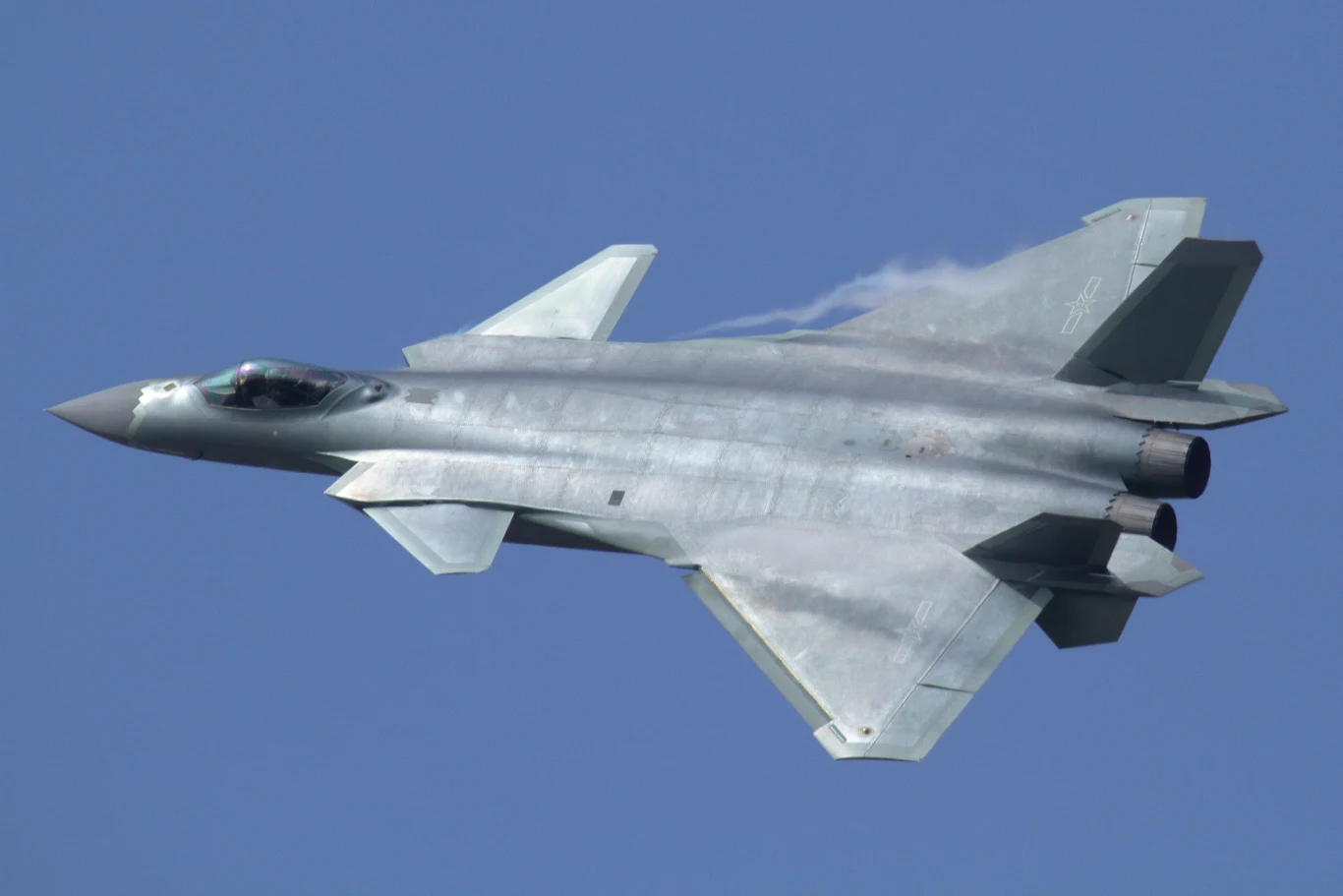 J-20 Soaring Dragon Nowoczesny myśliwiec odrzutowy o dwusilnikowej konstrukcji, charakteryzujący się smukłym kadłubem i bocznymi skrzydłami, lecący w powietrzu na tle bezchmurnego nieba.