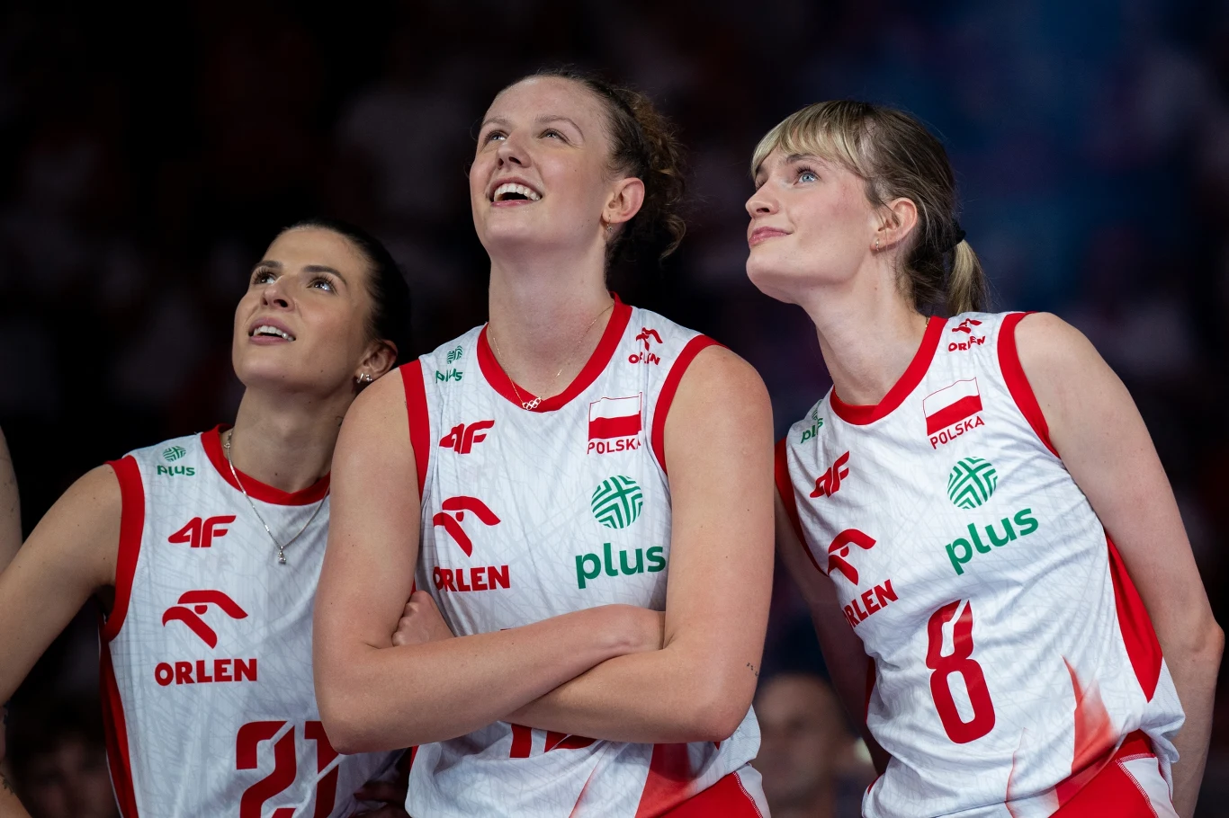 Alicja Grabka, Martyna Czyrniańska i Julita Piasecka Trzy zawodniczki reprezentacji Polski w siatkówce ubrane w białe stroje z czerwonymi detalami, stoją obok siebie i patrzą z uśmiechem w górę.